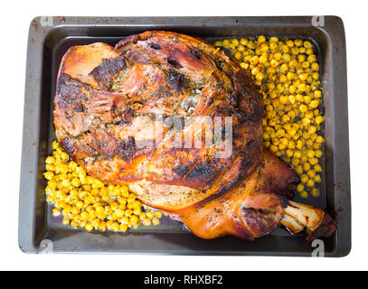 Ofen gebackene Schweinshaxe mit Kichererbsen auf Backblech. Auf weissem Hintergrund Stockfoto