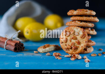 Runde orange Biscuits mit bunten kandierte Früchte und ein Stück saftige Orange liegen auf einem Holztisch Stockfoto