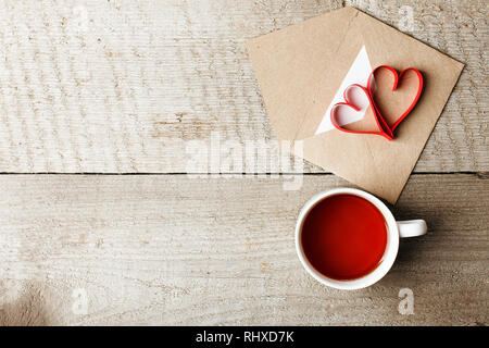 Tasse Tee mit roten Herzen und craft-Umschlag auf vintage Holz- Hintergrund schliessen. Valentines Tag. Guten Morgen warmong Konzept, zu kopieren, zu Stockfoto