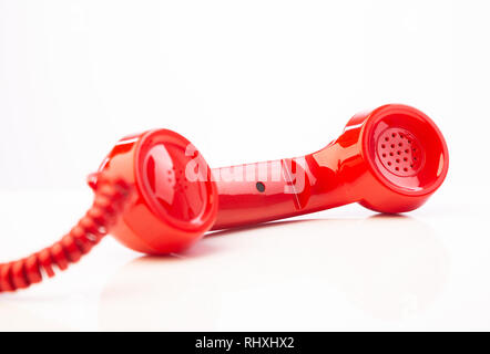 Ein rot Retro Telefonhörer liegend auf die Seite vor einem weißen Hintergrund. Stockfoto