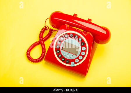 Ein rot Retro Telefon von oben vor einem gelben Hintergrund. Stockfoto