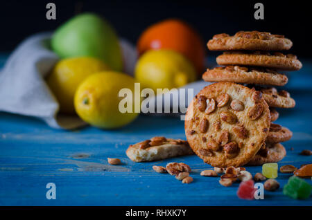 Runde orange Biscuits mit bunten kandierte Früchte und ein Stück saftige Orange liegen auf einem Holztisch Stockfoto