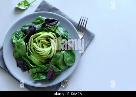 Salat mit Avocado, Spinat und Zuckerrüben Blätter auf grau Holz- Hintergrund. Vegetarisches Essen Konzept. Selektive konzentrieren. Stockfoto
