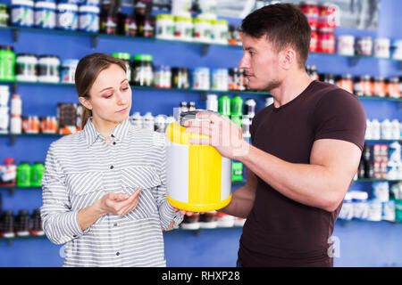 Junge positive körperlich fit Personen, die Sport Ernährung Produkte im Store Stockfoto