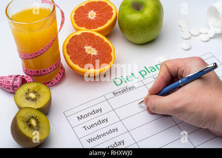 Der Arzt schreibt ein Rezept, um den Patienten, macht eine Diät Plan am Arbeitsplatz mit frischem Obst. Ansicht von oben, das Konzept der gesunden Ernährung. Stockfoto