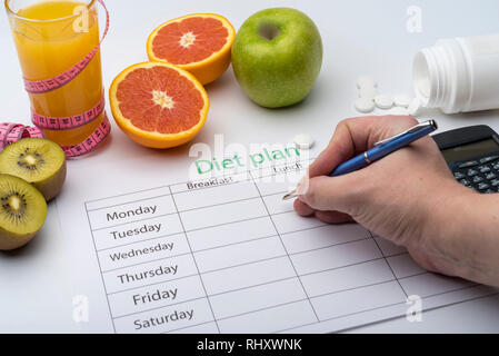 Der Arzt schreibt ein Rezept, um den Patienten, macht eine Diät Plan am Arbeitsplatz mit frischem Obst. Ansicht von oben, das Konzept der gesunden Ernährung. Stockfoto