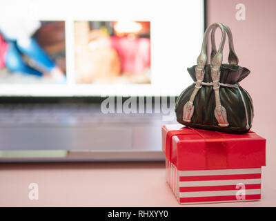 Kleines Geschenk Box mit schwarze Tasche in der Nähe von Laptop. Online Store Konzept Stockfoto