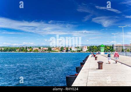 Adria Damm mit einem Leuchtturm und Touristen im Sommer in Zadar, Kroatien. Stockfoto