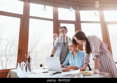 Erstellen neuer Stil. Eine Gruppe von drei Personen zu Design Studio. Afrikanische Frau mit Laptop in der Nähe des Kollegen Designer. Stockfoto