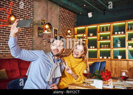 Selfie in einem teuren Restaurant. Junges Paar lächelnd und selfie Foto auf Telefon, während das Abendessen in Stockfoto