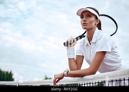 Junge schöne Tennisspieler in weißen Polo mit einem Schläger auf einem Gericht, entfernt. Gesunder Lebensstil Stockfoto