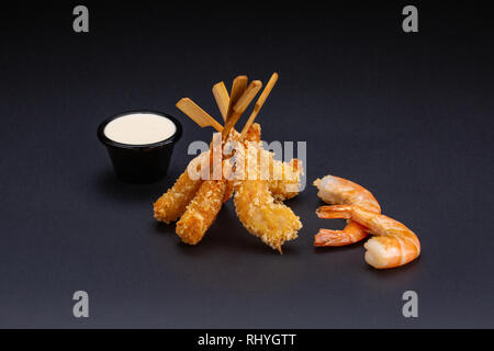 Tiger Garnelen im Teig. Ebi tempura mit pikanter Sauce auf dunklem Hintergrund. Gebratene Garnelen Stockfoto