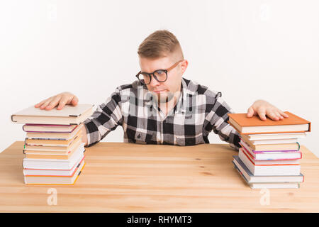 Menschen, Wissen und Bildung Konzept - Müde männliche Kursteilnehmer am Tisch sitzen mit Bergen von Büchern und will nicht bis zu Studie Stockfoto