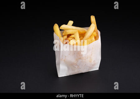 Pommes frites in einem White Paper Box auf schwarzem Hintergrund. Stockfoto