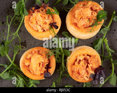 Blätterteiggebäcke mit einem würzigen, chunky Lachs Füllung, garniert mit Erbse Eintragfäden Stockfoto