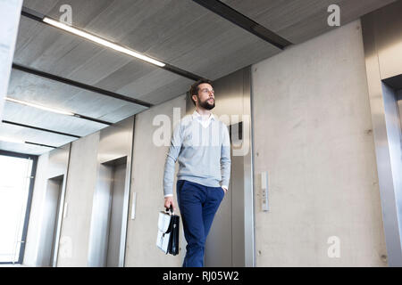 Zuversichtlich Geschäftsmann mit Aktenkoffer wandern in der Lobby im Büro Stockfoto