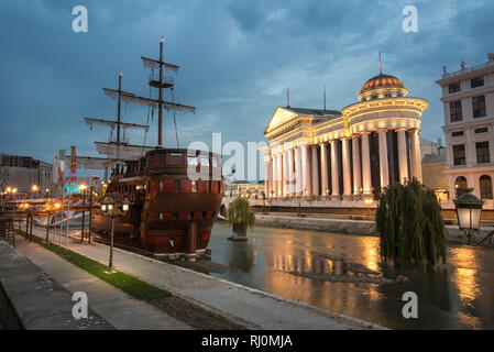 Das archäologische Museum von Mazedonien und die Brücke der Kulturen in der Nacht. Alte Schiff in den Fluss. Skopje, Republik Mazedonien Stockfoto