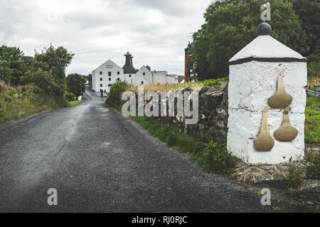 Close-up Hauptstraße der Laphroaig Distillery. Islay Insel, Schottland. Atemberaubende Landschaft Landschaft vor dem Regen. Der asphaltierte Weg zu den landwirtschaftlichen Gebäuden. Close-up weißes Tor Post mit Stone Fence. Stockfoto