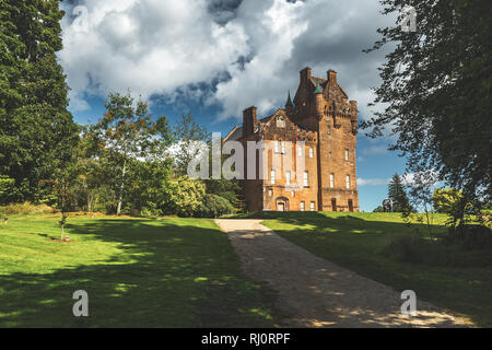 Pfad zu der alten Burg. Nordirland. Malerische Szene die vintage Gebäude, das von den grünen Rasen und Bäumen umgeben. Blauen bewölkten Himmel Hintergrund. Atemberaubende irische Landschaft. Historisches Haus. Stockfoto