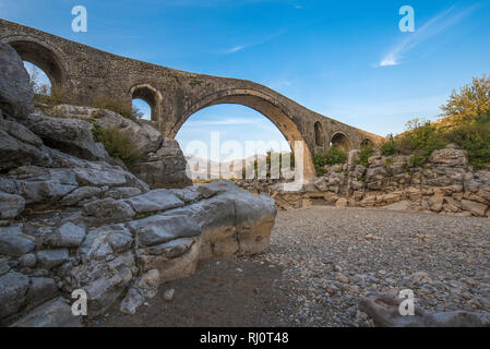Die mesi Brücke (Ura e Mesit) in Mes, Albanien, in der Nähe von Shkodra. Ein alter Stein osmanische Brücke - die größte im Land. Trockenen Fluss und die Berge Stockfoto