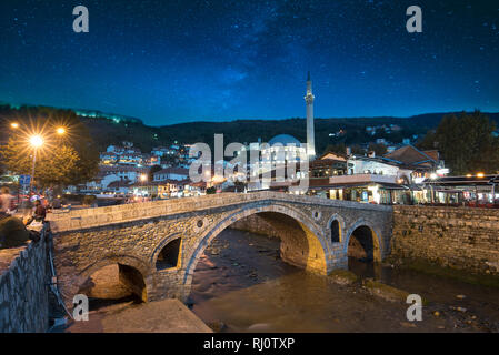 Nacht Blick auf alte steinerne Brücke und alten osmanischen Sinan Pascha Moschee in Prizren, Kosovo. Historische Stadt, Nacht Landschaft mit Star Sky nach Sonnenuntergang Stockfoto