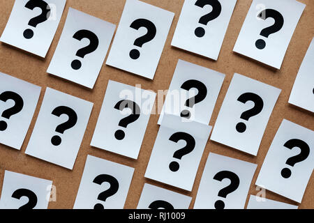 Fetten schwarzen Fragezeichen auf Papier Karten zufällig über einen hölzernen Hintergrund in einem konzeptionellen Bild verstreut Stockfoto