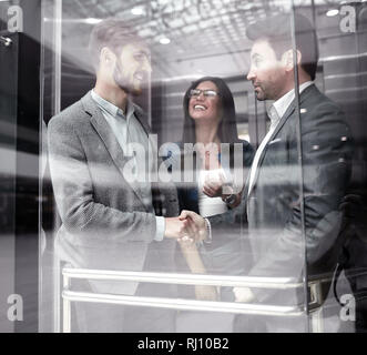Kolleginnen und Kollegen die Hände schütteln im Elevato Stockfoto