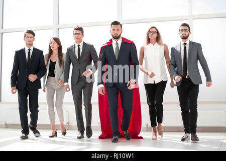 Geschäftsmann in einem roten Superhelden Umhang und seine Business Team Stockfoto