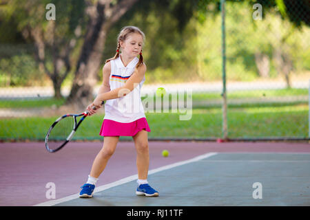Kind spielen Tennis auf Innen- Hof. Kleines Mädchen mit Tennisschläger und Ball im Sport Club. Aktive Bewegung für Kinder. Sommer Aktivitäten für Kinder. Stockfoto