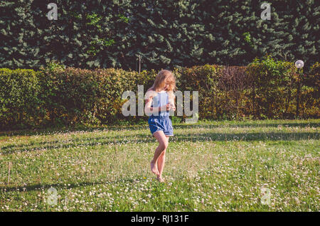 Adorable kleine Mädchen draußen in der Wiese voller Gänseblümchen Stockfoto