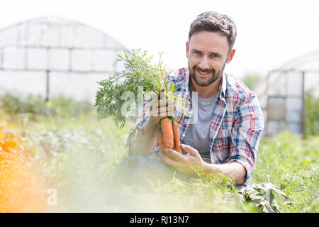 Portrait von lächelnden Mitte nach Bauern ernten Möhren am Bauernhof Stockfoto