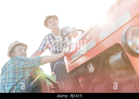 Low Angle Sicht der Bauern auf den Traktor gegen Himmel während der sonnigen Tag Stockfoto