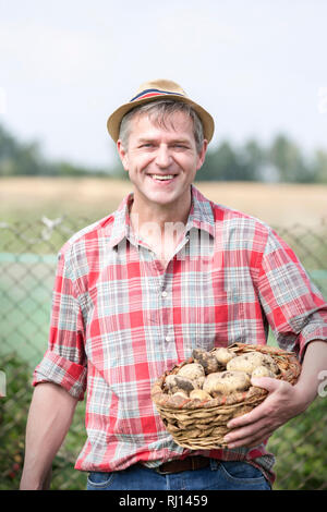 Portrait von lächelnden Landwirt, die biokartoffeln im Korb auf der Farm Stockfoto