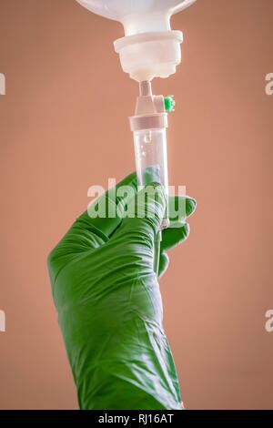 Krankenschwester, die Verwaltung von Flüssigkeit mit einer Pipette auf braunem Hintergrund Stockfoto