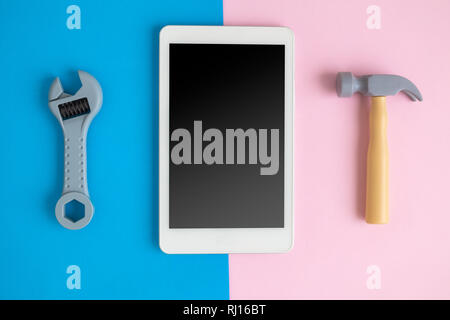 Digitale tablet device oder Handy mit Hammer und Schraubenschlüssel an Pastell-hintergrund minimale Technik Reparatur kreatives Konzept. Stockfoto