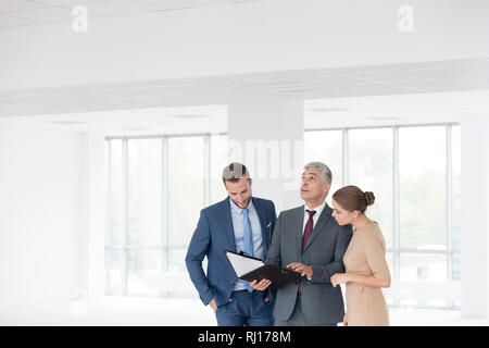 Zuversichtlich reifen Unternehmens diskutieren über Dokument mit jungen Kolleginnen und Kollegen im neuen Büro Stockfoto