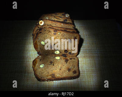 Brot mit Haselnüssen, getrockneten Aprikosen, Pflaumen und Rosinen liegt auf der Tischdecke. Still-Leben. Stockfoto