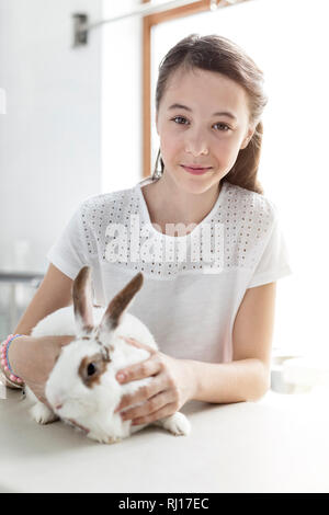 Portrait von Mädchen mit Hase auf Bett bei tierärztlichen Klinik Stockfoto