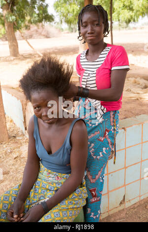 Samba Dorf, Provinz Yako, Burkina Faso; EIN Mitglied von Samatas Haushalt bereitet sich auf Zopf Haar. Stockfoto