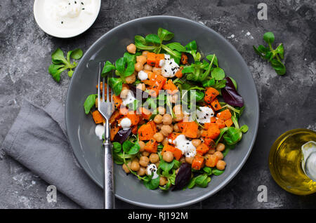 Gesunde vegetarische Salat, gerösteten Kürbis und Kichererbsen Salat in eine Schüssel auf grauem Hintergrund Stockfoto