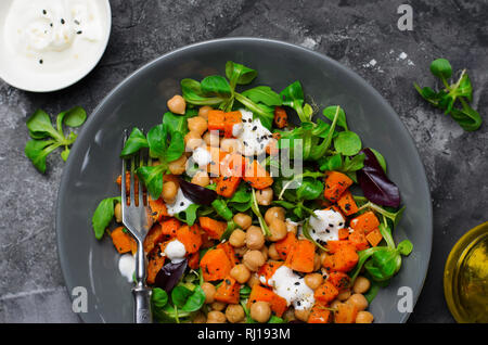 Gesunde vegetarische Salat, gerösteten Kürbis und Kichererbsen Salat in eine Schüssel auf grauem Hintergrund Stockfoto
