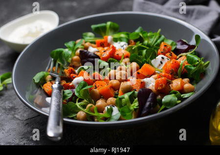 Gesunde vegetarische Salat, gerösteten Kürbis und Kichererbsen Salat in eine Schüssel auf grauem Hintergrund Stockfoto