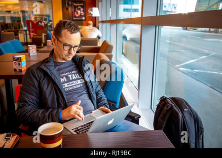 Prag, Tschechische Republik - 01.02.2019: schöner Mann am Tisch sitzen und Arbeiten am Laptop in Prag flughafen Cafe in der Tschechischen Republik Stockfoto