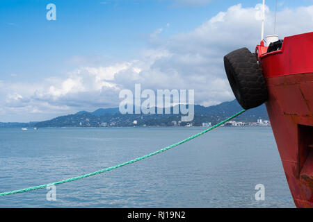 Blick auf die Skyline des Hafens von Batumi, Georgien mit Bergen und bewölkter Himmel, Teil der roten Boot an der Küste des Schwarzen Meeres in einem sonnigen Tag. Stockfoto