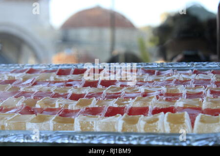 Schließen Sie herauf Bild eines Fachs von Zitrusfrüchten und Rose gewürzte türkische Köstlichkeiten in Cubes mit der Kuppel einer Hamam im Hintergrund in Safranbolu, Türkei. Stockfoto