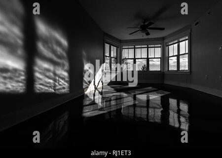 Am späten Nachmittag Sonne durch arge bay Windows erstellen Sie schöne Schatten und Spiegelungen auf glänzenden Vinyl Bodenbelag. Stockfoto