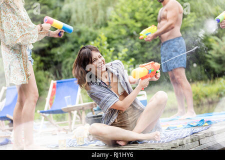 Fröhliche Paare genießen mit sprizen Gewehren auf Pier im Sommer Stockfoto