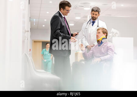 Reifen Spezialist im Gespräch mit Patienten im Rollstuhl im Krankenhaus Stockfoto