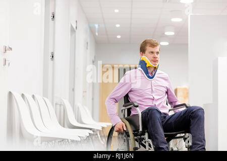 Junger Mann mit Neck Brace sitzen auf Rollstuhl im Krankenhaus Flur Stockfoto