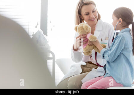 Lächelnd Arzt, der teddybär zum Mädchen im Krankenhaus Stockfoto